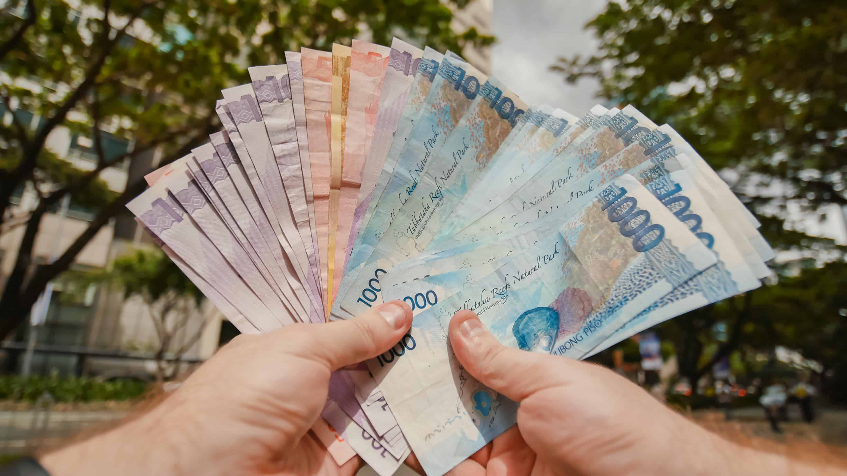 Филиппинские деньги. Филиппинец с деньгами. Филиппинские песо в руках. Деньги Филиппин фото. Синие деньги.